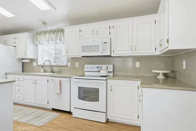 a kitchen with granite countertop white cabinets and white appliances