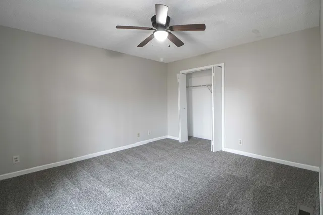 a view of an empty room and chandelier fan