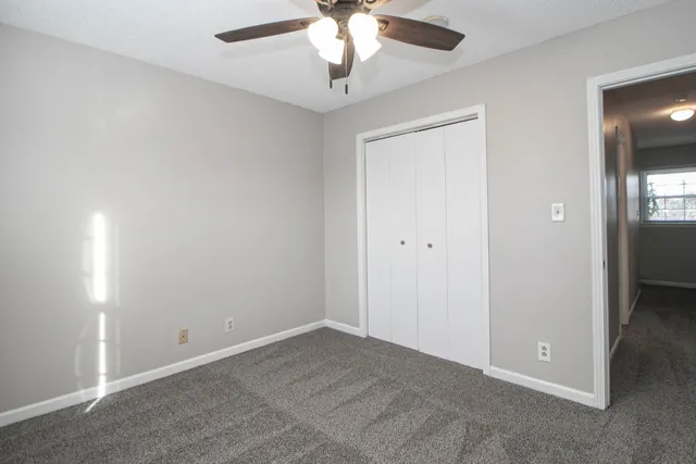 an empty room with a fan & a ceiling fan
