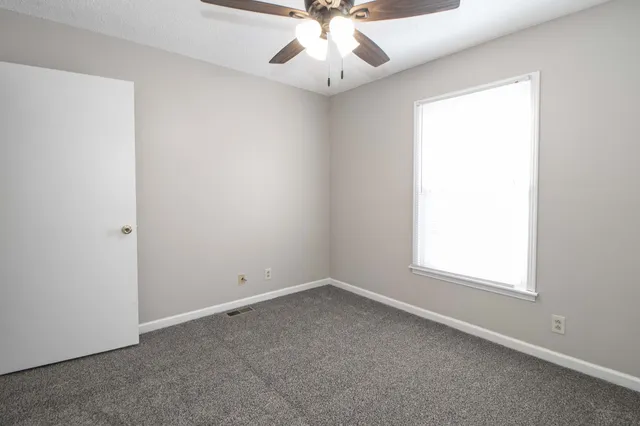 an empty room with a window and a fan