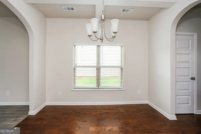 an empty room with chandelier fan and windows