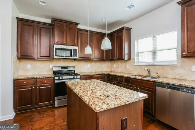 a kitchen with stainless steel appliances granite countertop a sink stove and microwave