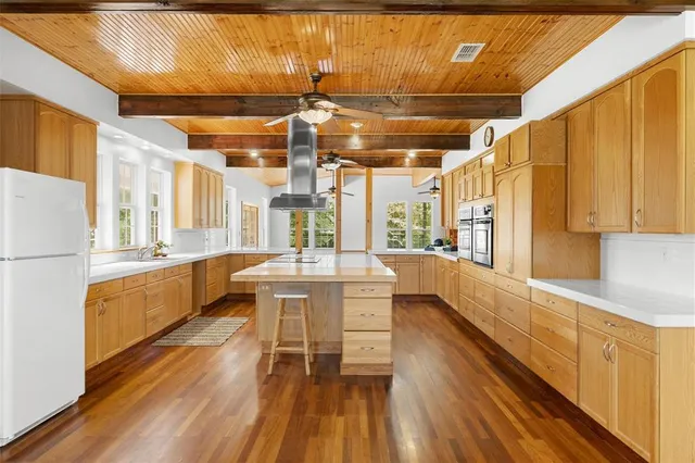 a large white kitchen with wooden floor and stainless steel appliances