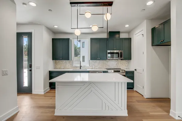 a kitchen with stainless steel appliances granite countertop a sink a stove and a refrigerator