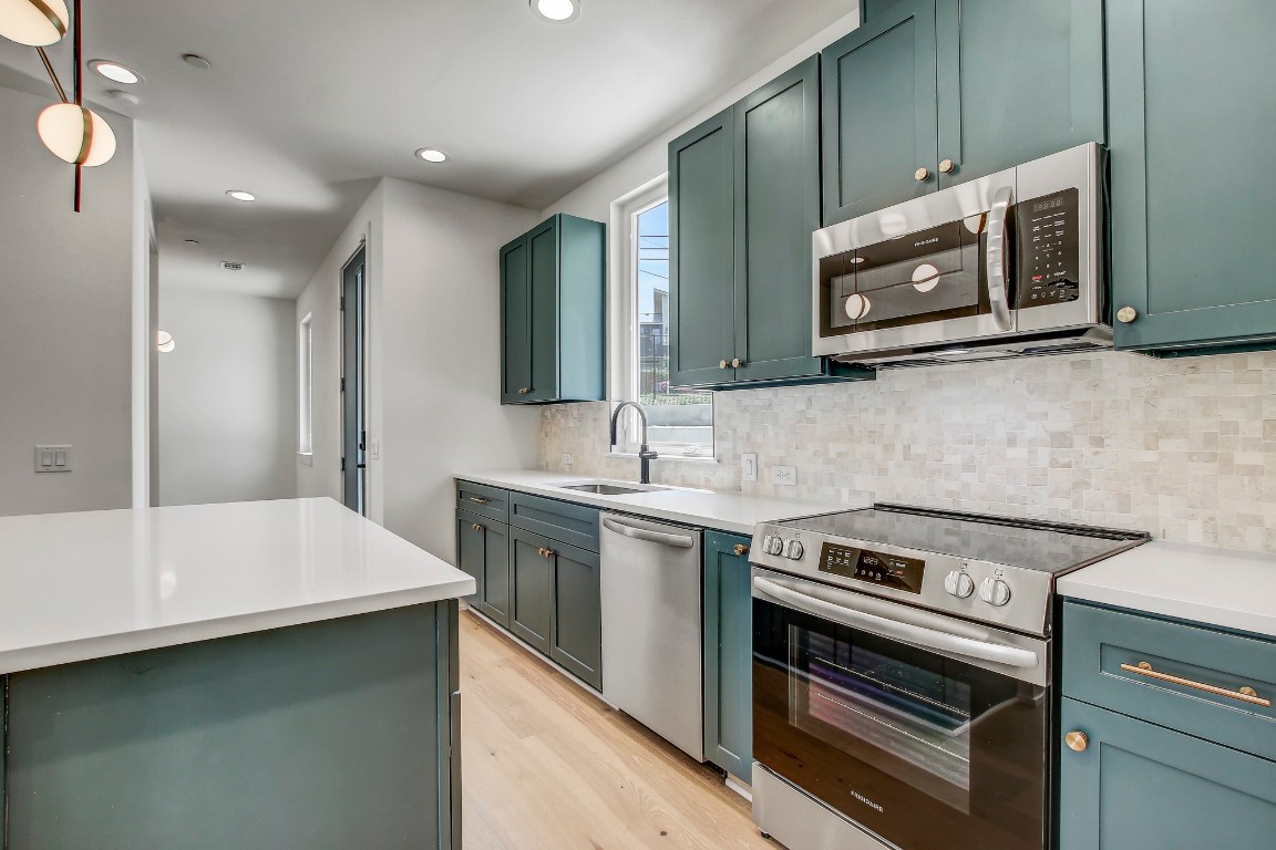 4127 East 12th Street, Unit 5 Austin, TX 78721 - Photo 13 of 33 Kitchen with stainless steel appliances, light wood finished floors, tasteful backsplash, a sink, and recessed lighting