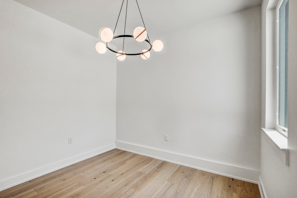 4127 East 12th Street, Unit 5 Austin, TX 78721 - Photo 17 of 33 Unfurnished room featuring light wood-type flooring, baseboards, and a chandelier
