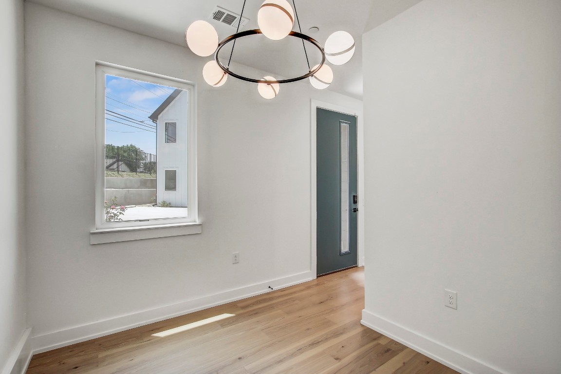 4127 East 12th Street, Unit 5 Austin, TX 78721 - Photo 18 of 33 Spare room featuring light wood-type flooring, baseboards, and a chandelier
