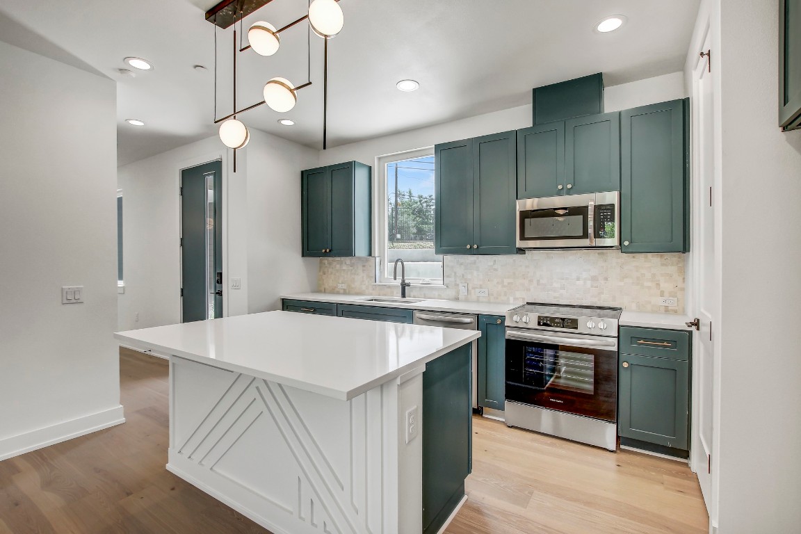 4127 East 12th Street, Unit 5 Austin, TX 78721 - Photo 2 of 33 Kitchen featuring stainless steel appliances, tasteful backsplash, light wood-type flooring, a sink, and light countertops