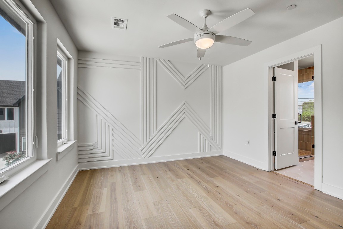 4127 East 12th Street, Unit 5 Austin, TX 78721 - Photo 21 of 33 Unfurnished room featuring light wood-type flooring, a decorative wall, ceiling fan, and baseboards