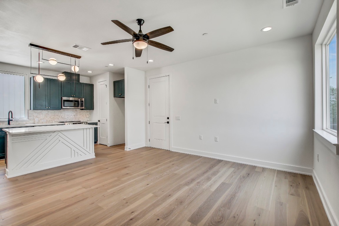 4127 East 12th Street, Unit 5 Austin, TX 78721 - Photo 4 of 33 Kitchen with stainless steel microwave, backsplash, a ceiling fan, light countertops, and baseboards