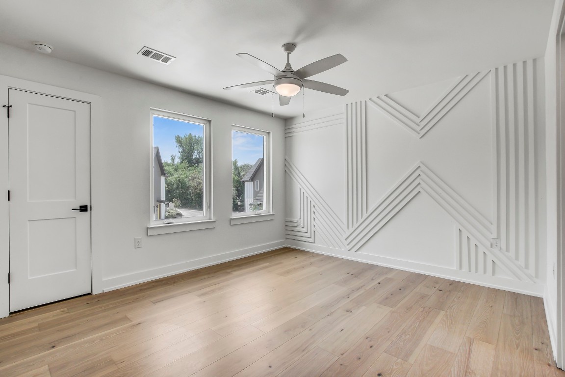 4127 East 12th Street, Unit 5 Austin, TX 78721 - Photo 7 of 33 Empty room featuring ceiling fan, a decorative wall, light wood-type flooring, baseboards, and a smoke detector