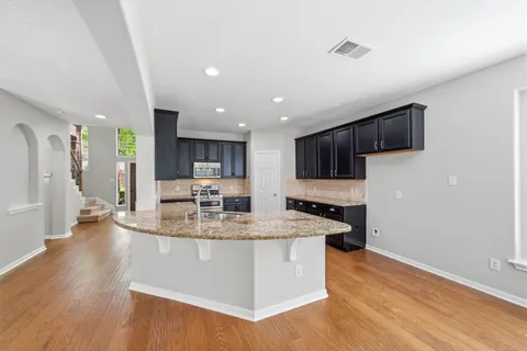 a kitchen with stainless steel appliances granite countertop a sink a stove top oven a counter space and cabinets