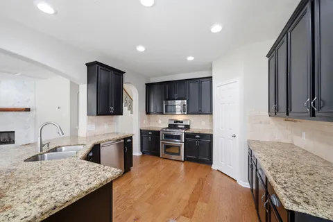 a kitchen with stainless steel appliances granite countertop a sink stove and refrigerator