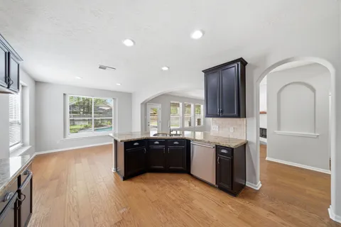 a large kitchen with stainless steel appliances granite countertop a sink and wooden cabinets
