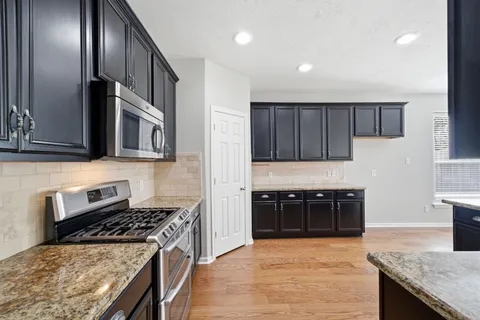 a kitchen with stainless steel appliances granite countertop a stove a sink and a refrigerator