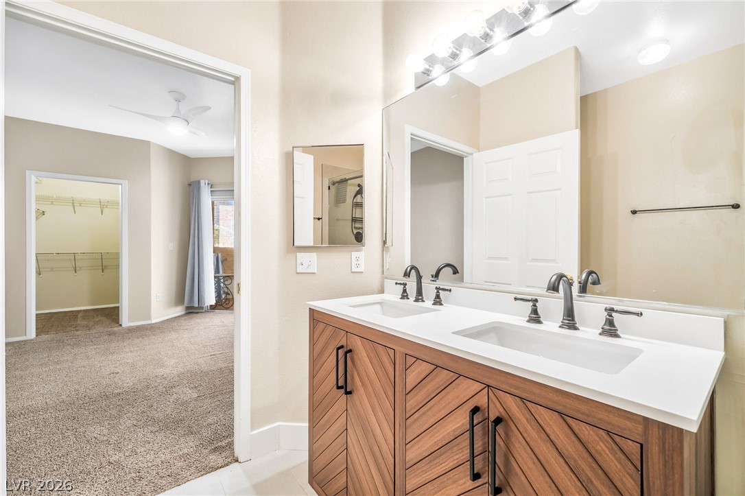 2050 West Warm Springs Road, Unit 2411 Henderson, NV 89014 - Photo 22 of 37 A chic vanity with dual sinks, sleek faucets, and striking wood cabinetry provides sophisticated bathroom utility.