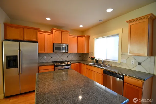 a kitchen with stainless steel appliances granite countertop a sink refrigerator stove and microwave