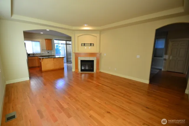a view of empty room with wooden floor and fireplace