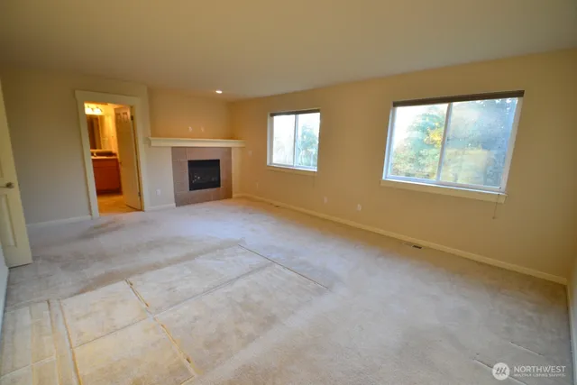 an empty room with windows and fireplace