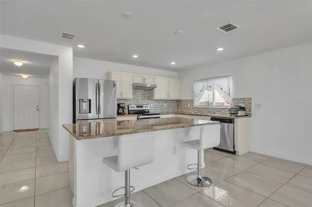 a kitchen with stainless steel appliances granite countertop a sink and a refrigerator