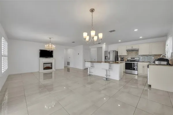a view of a kitchen with kitchen island granite countertop a sink cabinets and stainless steel appliances