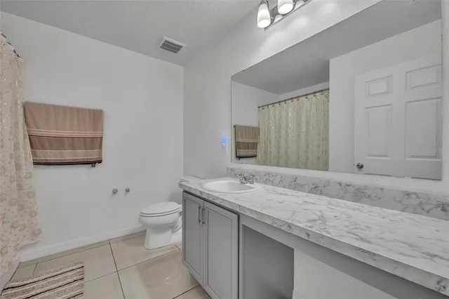 a bathroom with a granite countertop sink a toilet and a mirror