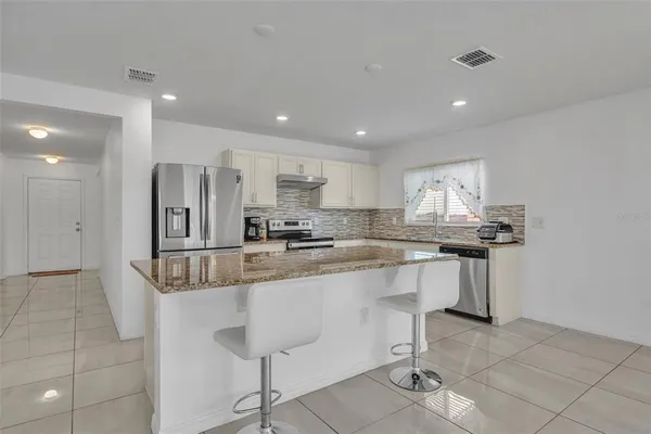 a kitchen with stainless steel appliances granite countertop a sink and a refrigerator