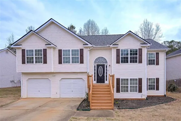 a view of a house with a yard and large tree