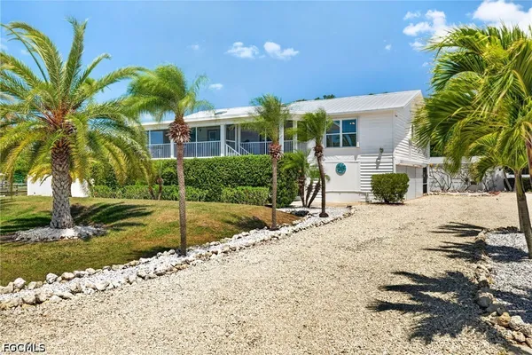 a front view of a house with garden and trees