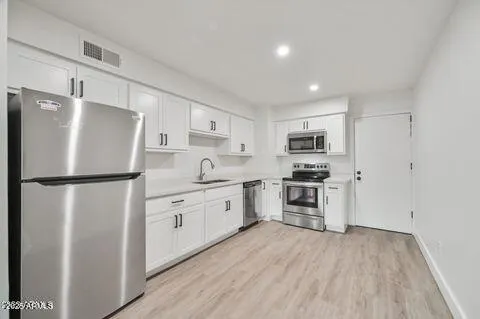 a kitchen with refrigerator and white cabinets