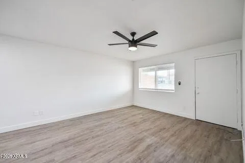 an empty room with wooden floor ceiling fan and windows