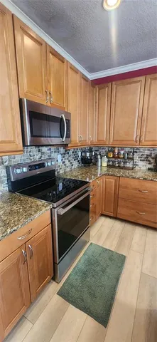 a kitchen with stainless steel appliances granite countertop a stove a sink and a microwave
