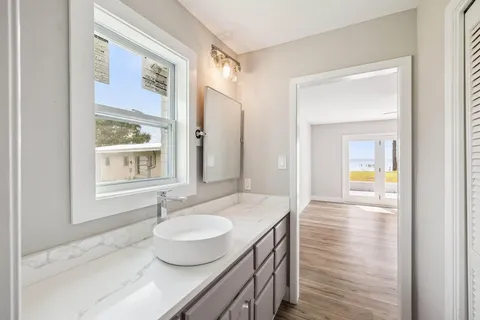 an empty room with wooden floor fan and windows