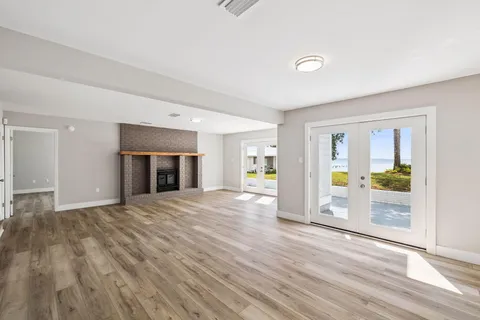 a view of an empty room with window and wooden floor