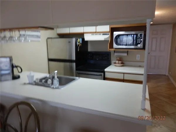 a kitchen with stainless steel appliances kitchen island granite countertop a refrigerator a sink and wooden cabinets