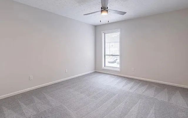 an empty room with windows and fan