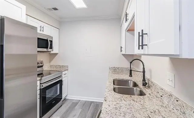 a kitchen with granite countertop a sink stainless steel appliances and cabinets