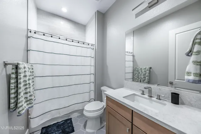 a bathroom with a granite countertop sink a toilet and mirror
