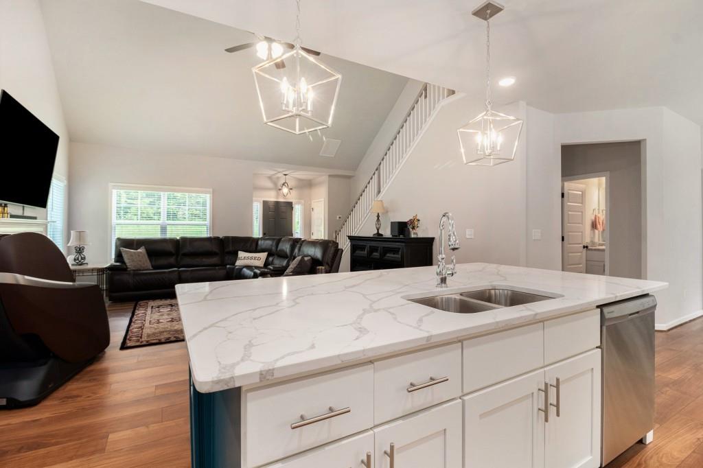 124 Willington Way Newnan, GA 30265 - Photo 11 of 41 a kitchen with a sink dishwasher a dining table and chairs with wooden floor