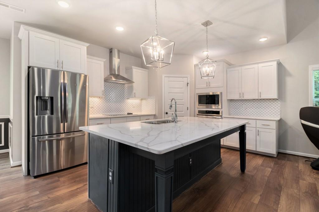 124 Willington Way Newnan, GA 30265 - Photo 7 of 41 a kitchen with kitchen island a center island wooden floor and stainless steel appliances