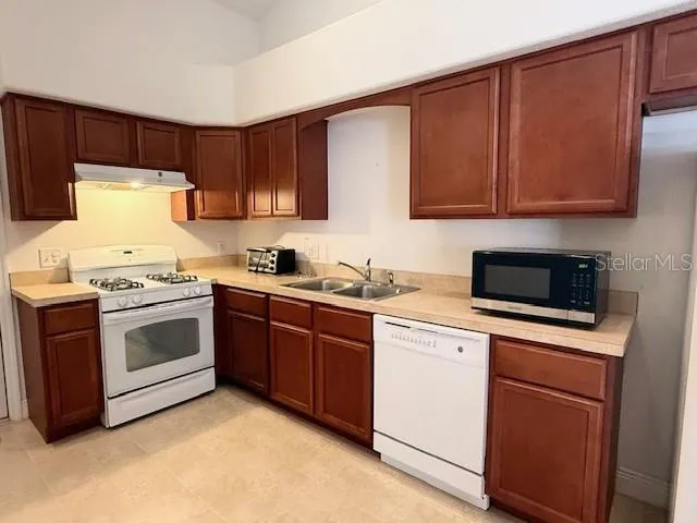 a kitchen with stainless steel appliances granite countertop a stove a sink and a microwave