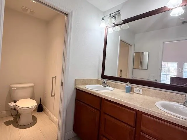 a bathroom with a granite countertop sink a toilet and a mirror