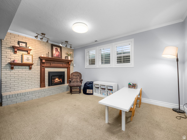523 Mountain View Road Centerville, UT 84014 - Photo 16 of 33 Living Area featuring brick wall, carpet flooring, ornamental molding, and a brick fireplace