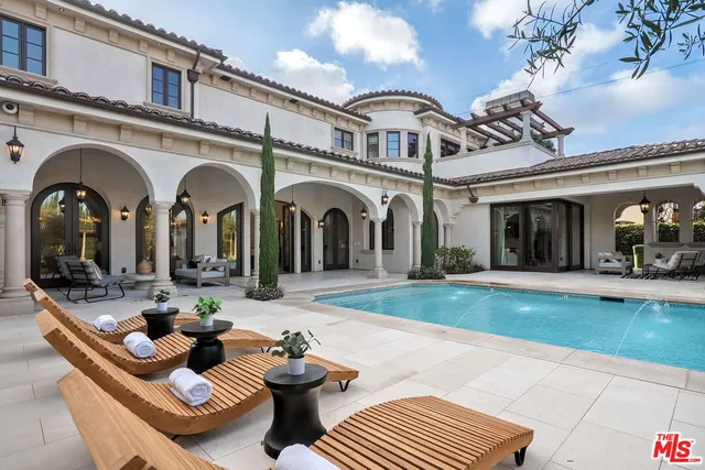 a view of swimming pool with outdoor seating and house in the background