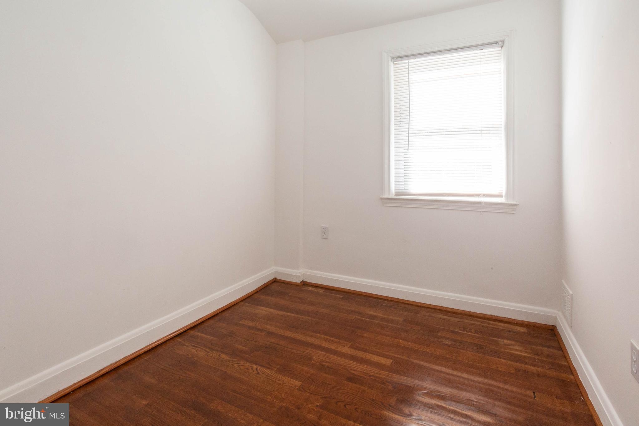 1327 Limit Avenue Baltimore, MD 21239 - Photo 12 of 24 an empty room with wooden floor and windows