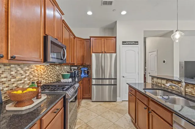 a kitchen with stainless steel appliances granite countertop a sink stove and refrigerator