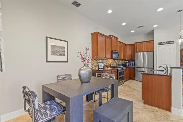 a kitchen with stainless steel appliances granite countertop a stove a refrigerator a kitchen island a table and chairs
