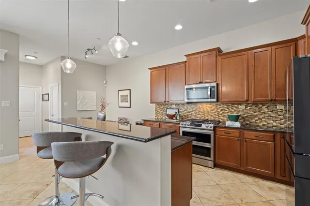 a kitchen with stainless steel appliances granite countertop a sink a stove a dining table and chairs