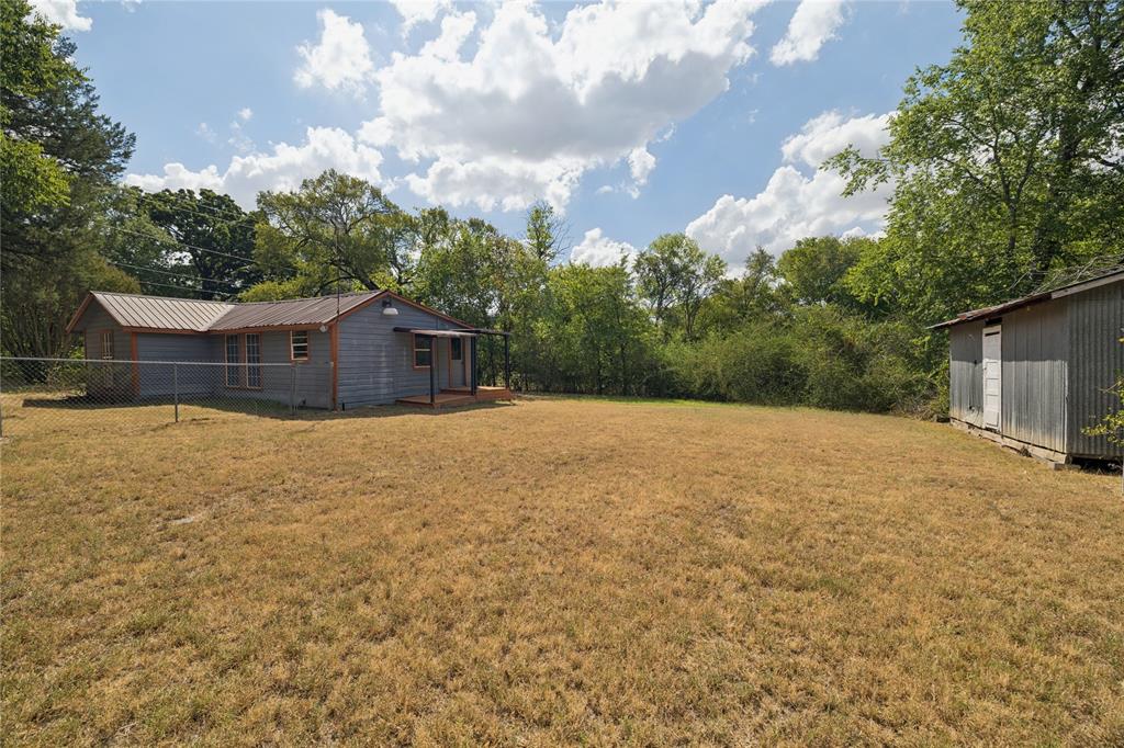 406 Carter Road Malakoff, TX 75148 - Photo 11 of 13 Metal roof residence featuring a covered porch, chain-link fencing, and a separate storage shed
