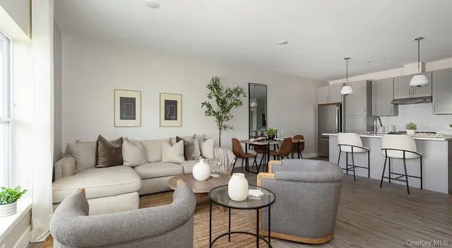 a living room with furniture kitchen view and a wooden floor